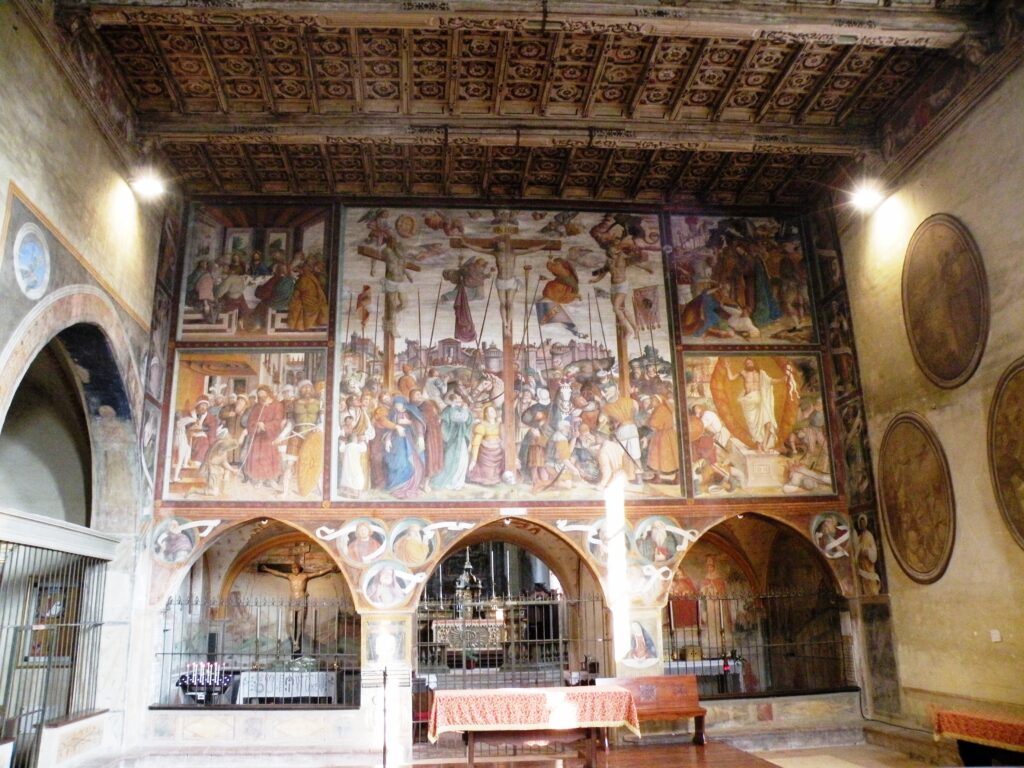 L'interno della chiesa francescana, affrescata dal pittore caravaggino Fermo Stella, uno dei numerosi pittori originari del paese, che avrebbe dato al mondo numerosi artisti, impresari edili e muratori. Le immagini di questo edificio furono certamente osservate dal piccolo Michelangelo